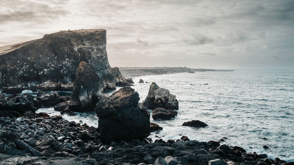 Breathtaking view of Iceland's rugged coastal cliffs and the vast North Atlantic Ocean during a cloudy day.