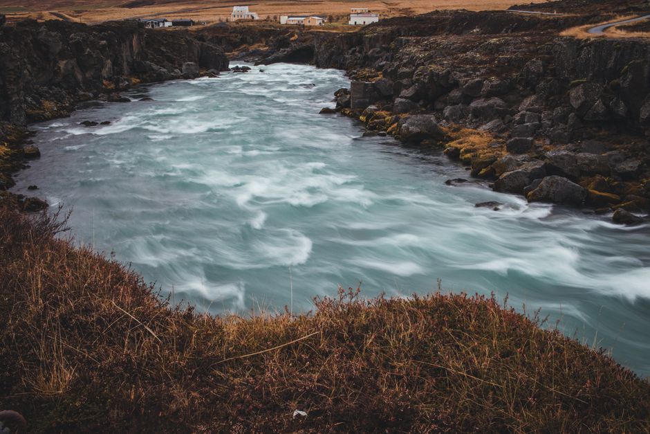 Serene Icelandic river flowing through a rocky landscape under a cloudy sky.