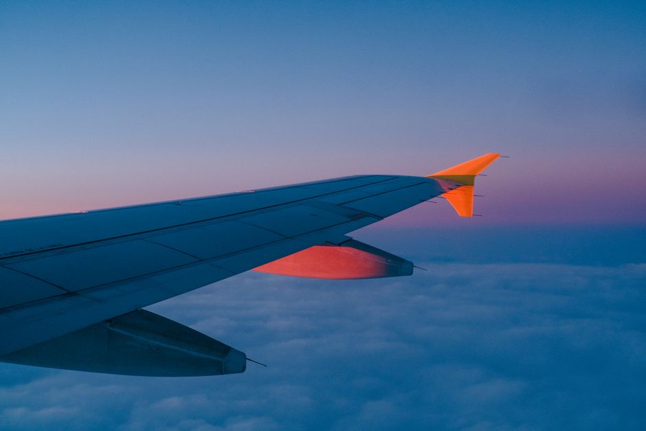 Aircraft wing above the clouds at sunset on a long-haul flight