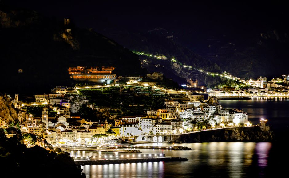 Breathtaking nightscape of a coastal town in Italy, illuminated beautifully along the shoreline.