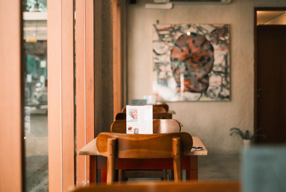 Warm and inviting café interior featuring wooden chairs and abstract artwork on the wall.
