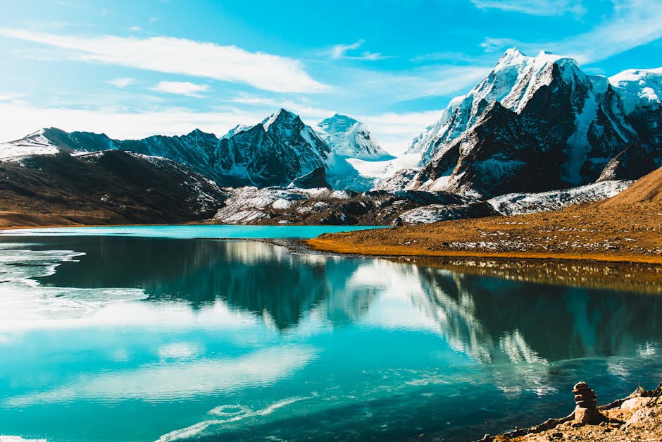 Vibrant mountain and lake scenery with snow-capped peaks reflecting in a serene turquoise lake.