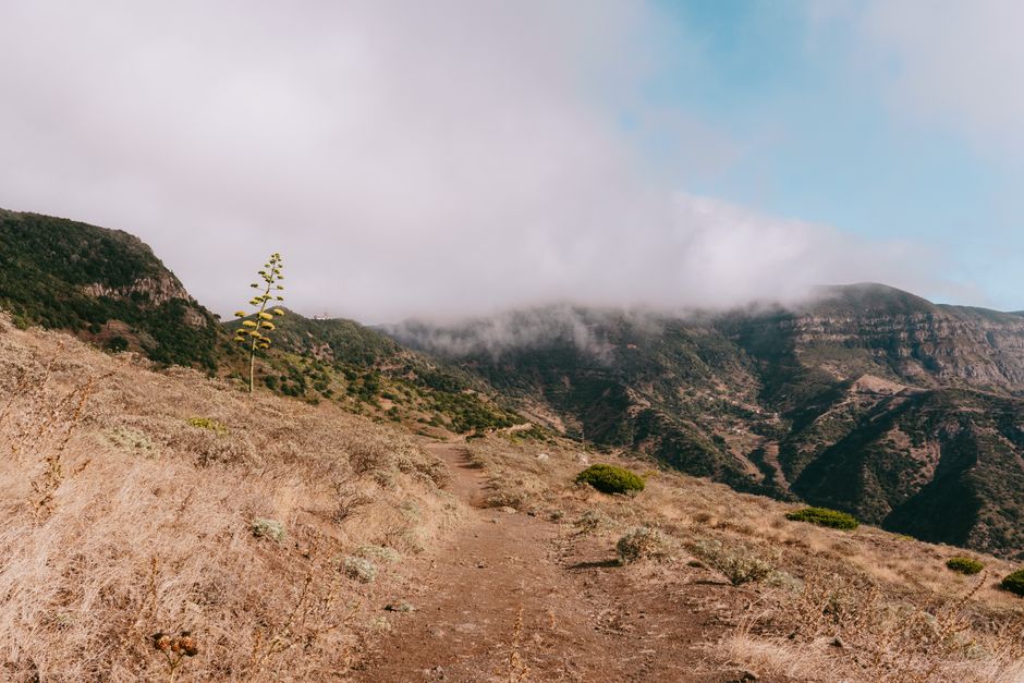 Explore the serene mountain landscape of Epína, Canarias with misty clouds and rugged trails.