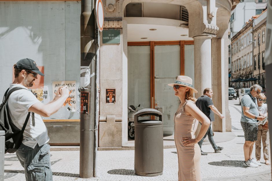A couple posing for a photo on bustling Santa Catarina Street in Porto, Portugal.