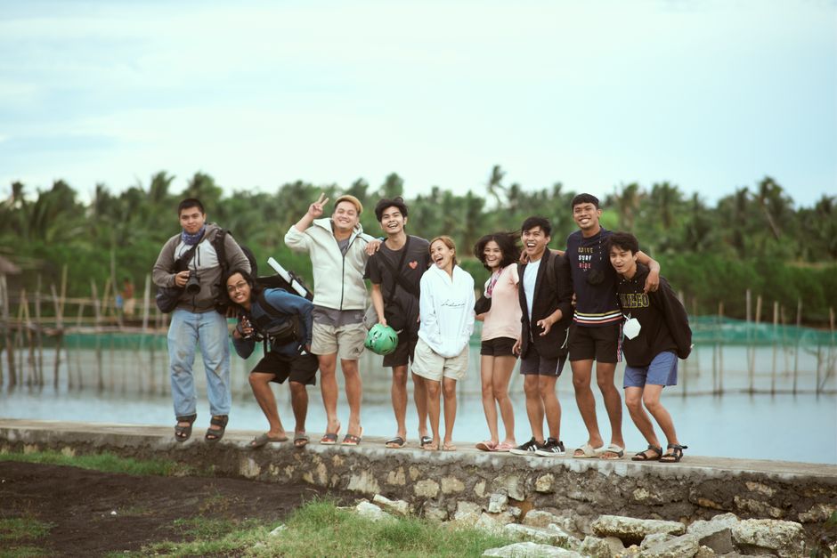 Happy group of diverse friends smiling together outdoors by a lake.