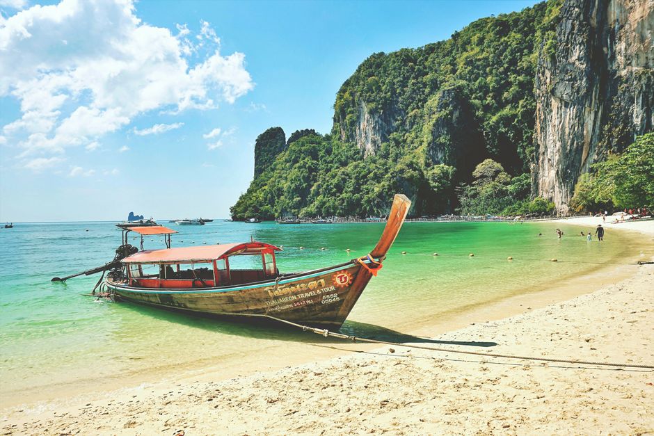 Idyllic Krabi beach scene with a traditional longtail boat and stunning limestone cliffs.