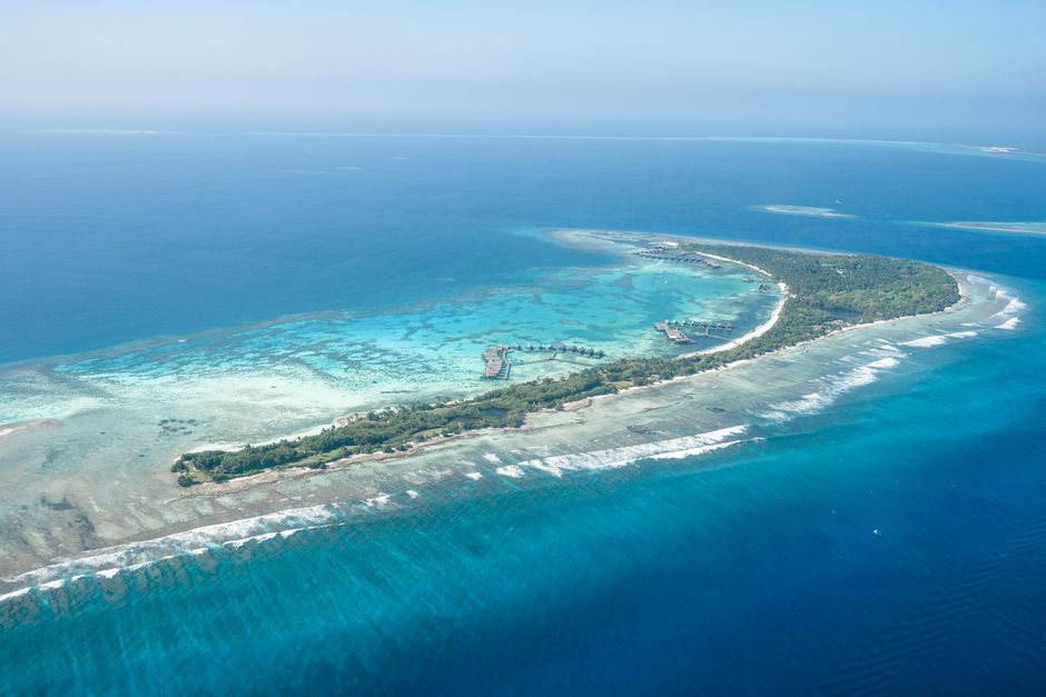 Stunning aerial shot of a tropical island surrounded by clear blue waters in the Maldives.