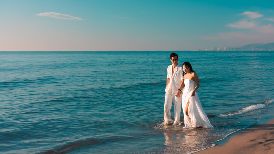 A couple enjoys a romantic walk on the beach at Đà Nẵng, Vietnam, with serene ocean views.