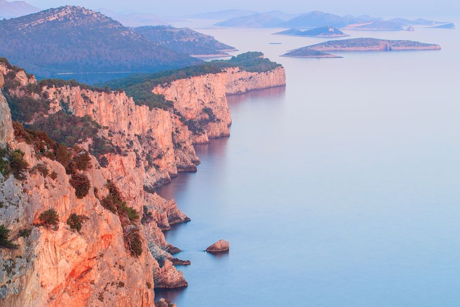 Stunning aerial view of Adriatic cliffs and serene sea with distant islands at dusk.