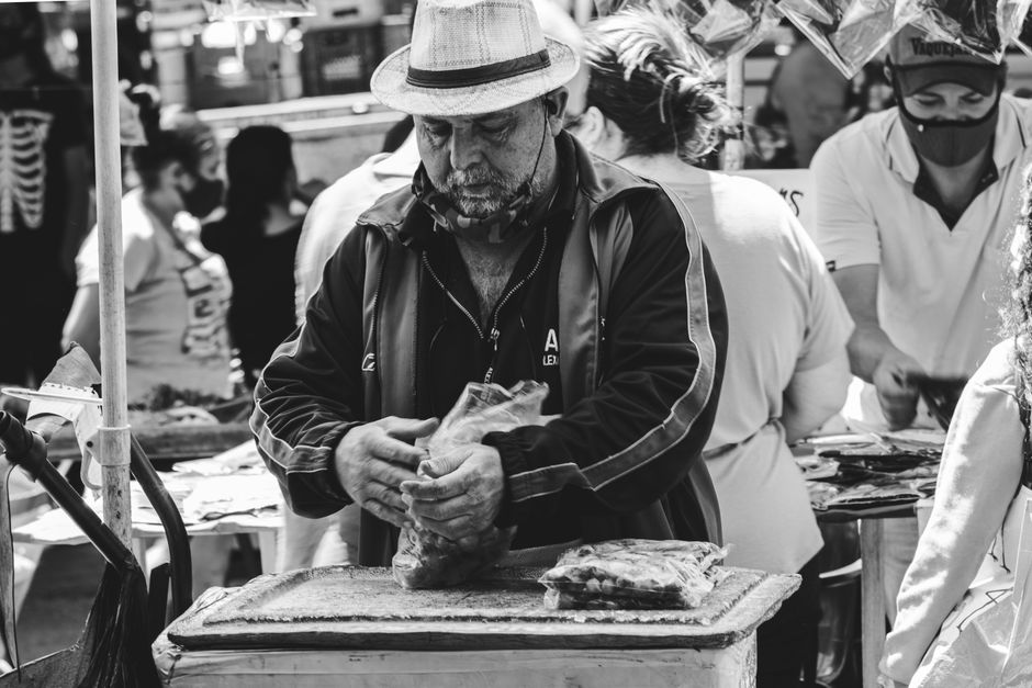 Black and white photo of a merchant at a vibrant street market in São Paulo, Brazil.