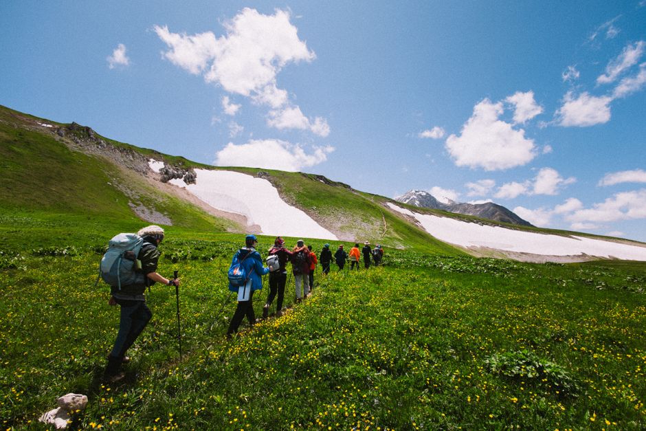 A group of hikers exploring a lush green mountain landscape on a sunny day.