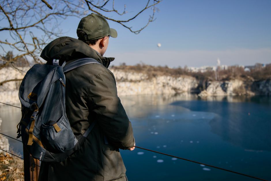 A person enjoying a scenic view of Kraków's quarry lake on a clear day, reflecting urban landscapes.