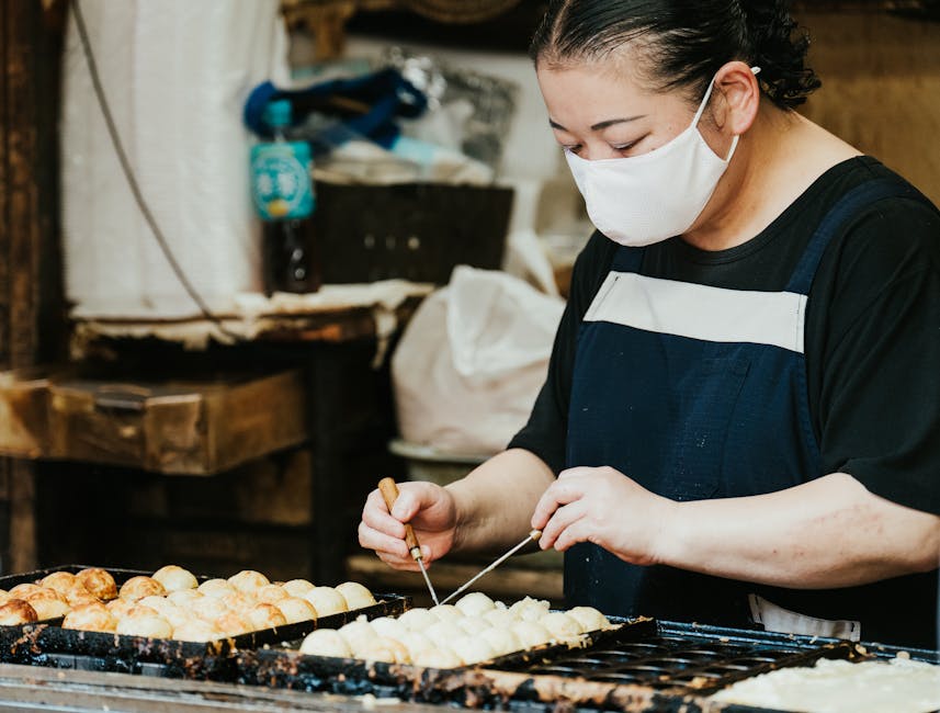 A Japanese street food vendor skillfully prepares takoyaki at an outdoor market.