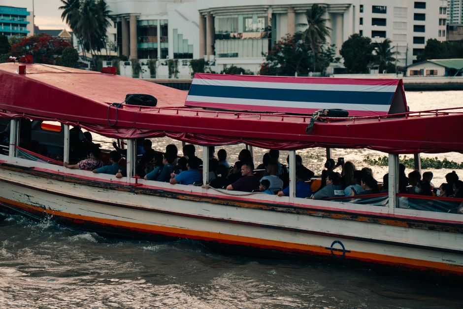Passengers commute on a boat along the Chao Phraya River in Bangkok, a vibrant aspect of city life.
