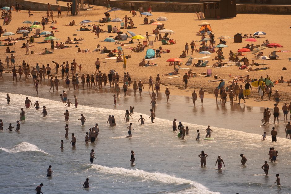 Aerial view of a crowded beach with people enjoying a sunny summer day.