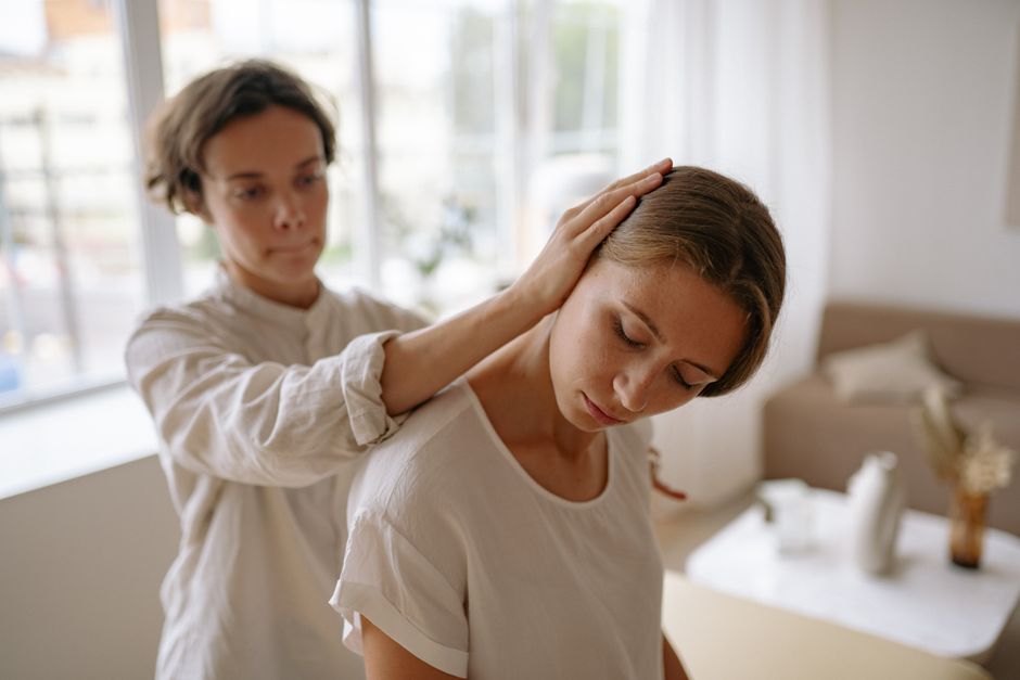 A therapist gently assists a client with a relaxation technique in a calm indoor setting.