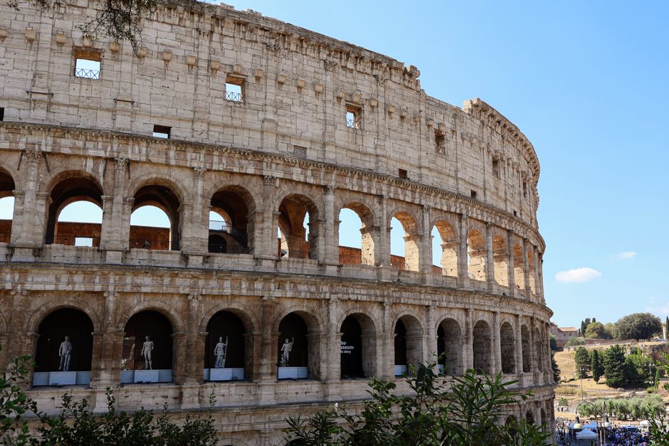 Close-up of the Colosseum's arched facade in Rome with clear blue sky.