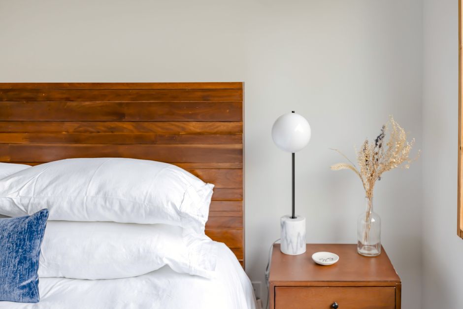 Elegant bedroom setup with wooden headboard and stylish decor on bedside table.