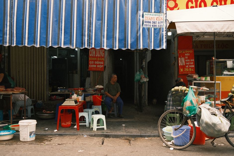 Lively street market featuring food vendors, awnings, and a parked bicycle.