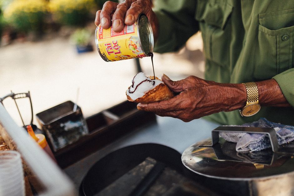 Close-up of a vendor preparing Vietnamese street food with coconut and sauce in Kon Tum.