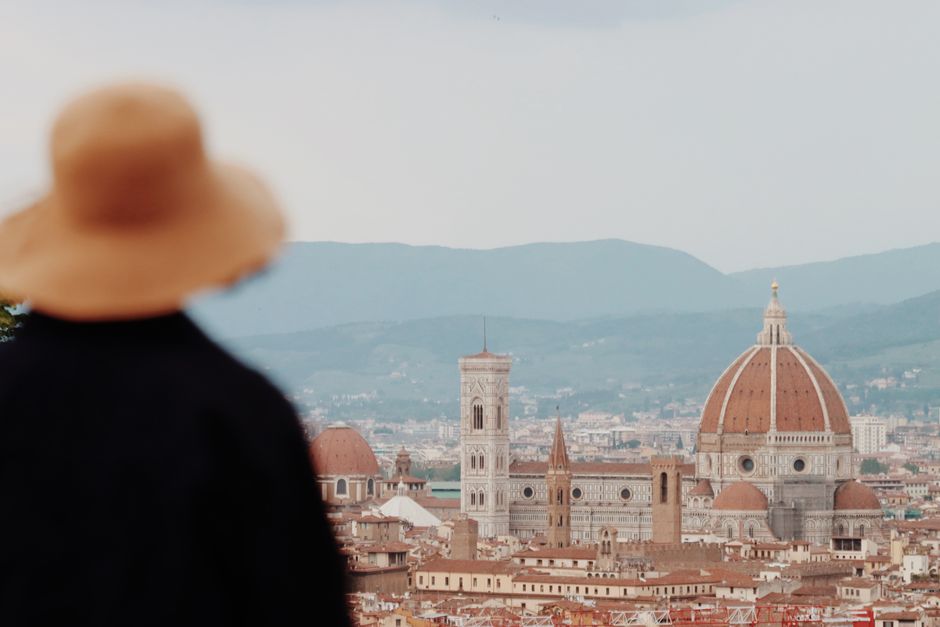 A woman in a hat views the iconic Florence skyline featuring the Duomo.
